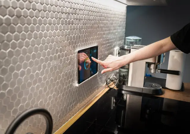 Modern kitchen with a touchscreen smart home control panel on the wall