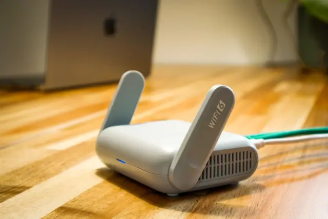 Modern WiFi router with antennas on a wooden desk in a home office